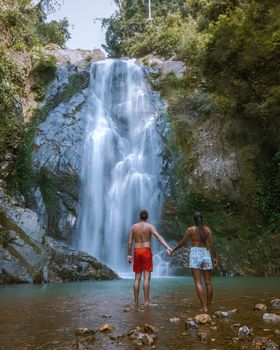 couple hiking to waterfall in Thailand, A tourist is enjoying the beauty of the waterfall in Chumphon province, Thailand , Klongphrao waterfall Thailand 