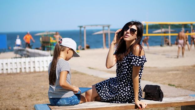 portrait, beautiful girl, woman in sun glasses talking on a mobile phone. on the beach, on a hot summer day,. High quality photo