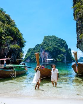 Koh Lao Lading near Koh Hong Krabi Thailand, a beautiful beach with longtail boats, a couple of European men, and an Asian woman on the beach. Couple on a boat trip