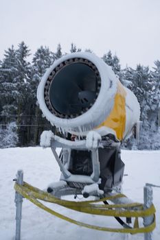 Yellow artificial snow cannon under snow on Wasserkuppe in Rhoen Hesse Germany ski resort on snowy mountain after fresh snow fall. High quality photo