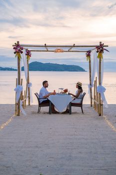 Romantic dinner on the beach in Phuket Thailand, couple man and woman mid age Asian woman and European man having dinner on the beach in Thailand during sunset.