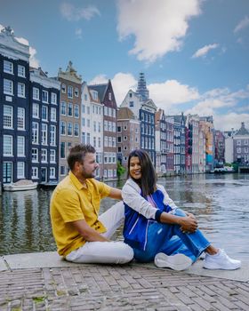 Amsterdam Netherlands, happy couple man and woman on a summer evening at the canals of Amsterdam. Man and woman mid age Asian girl and European men on a city trip in Amsterdam Netherlands