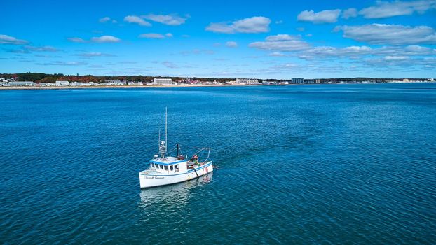 Image of Fishing boat off coast of Maine with distant view of coast
