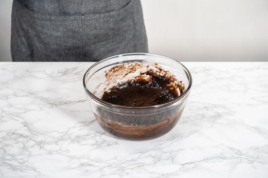 Mixing ingredients in a large glass mixing bowl to bake chocolate peppermint cupcakes.