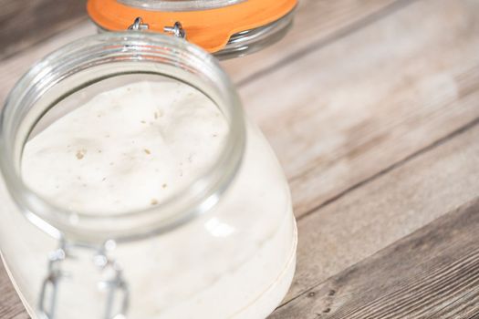 Feeding sourdough starter in a glass mason jar for baking artisan bread.