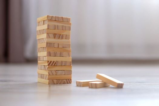 A tower of wooden blocks on the floor in room . Family board games