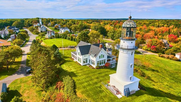 Image of Pair of white lighthouses on hill with homes and fall foliage