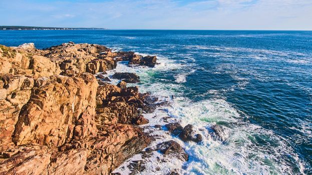 Image of Cliffs of ocean in Maine with waves crashing over boulders
