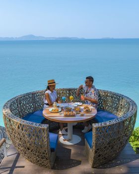 couple having lunch at a restaurant looking out over the ocean of Pattaya Thailand, man and woman having dinner in a restaurant by the ocean in Pattaya during summer