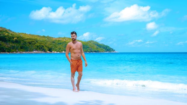 Praslin Seychelles tropical beach with palm trees, young men on a tropical beach with palm trees, white beach man walking Seychelles Island, tanning men on a tropical vacation