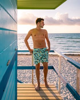 Miami beach Florida, young men on the beach with a colorful lifeguard hut, a man watching the sunset at the beach