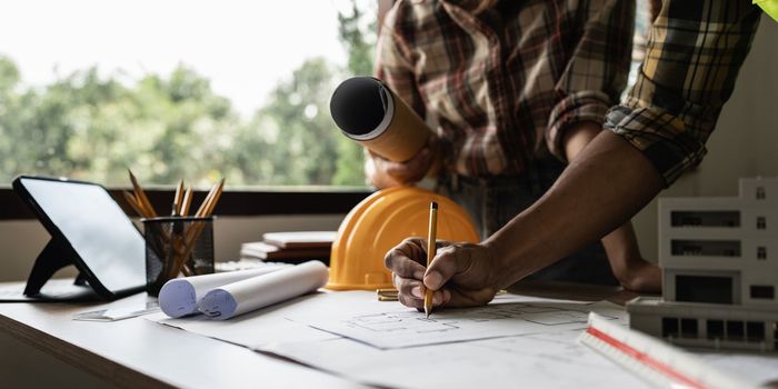 Architect man working with blueprints for architectural plan, engineer sketching a construction project concept.