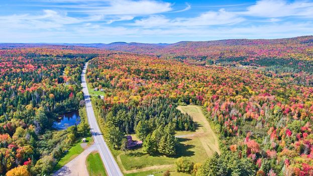 Image of Aerial road going through endless colorful fall hills and mountains of New York