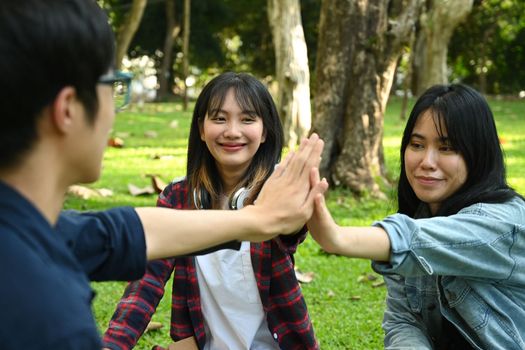 University students are giving high five, celebrating together. University, youth lifestyle and friendship concept.