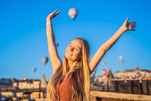 Tourist woman looking at hot air balloons in Cappadocia, Turkey. Happy Travel in Turkey concept. Woman on a mountain top enjoying wonderful view.