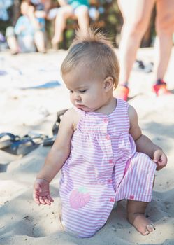 Adorable newborn baby playing on the beach.