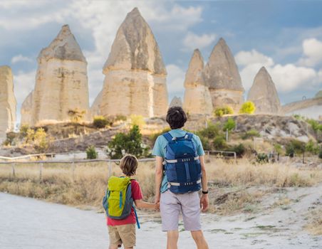 Father and son tourists on background of Unique geological formations in Love Valley in Cappadocia, popular travel destination in Turkey. Traveling with children in Turkey concept.