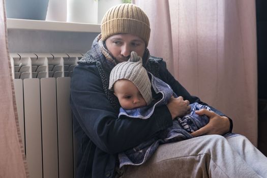 Man wearing warm clothing feeling cold checking central heating battery. Energy crisis in Europe