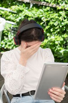 Sad girl listens to music from a tablet at a table in a cafe, High quality photo