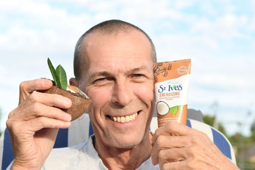 ST. Ives Fresh Energizing Coconut and Coffee Scrub in Tube, middle-aged man demonstrates facial scrub, As,Belgium, August 13,2022, High quality photo