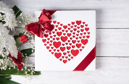 Valentine's day gift, red heart praline box and flower bouquet on white wooden table. High quality photo