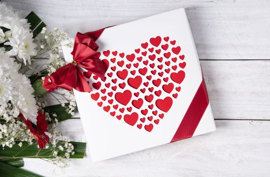 Valentine's day gift, red heart praline box and flower bouquet on white wooden table. High quality photo
