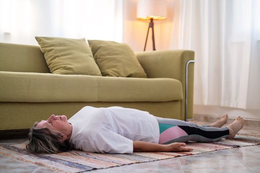 senior woman doing warmup workout at home. Fitness woman doing stretch exercise stretching her body. Elderly woman living an active lifestyle. 