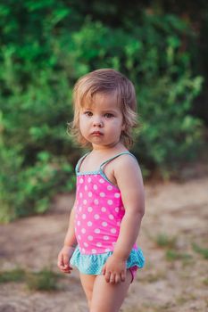 Charming baby in swimsuit by the river.