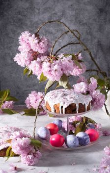 beautiful Easter cake on the table, and colored eggs, homemade cakes, still life with a silver teapot on a background of pink sakura. High quality photo