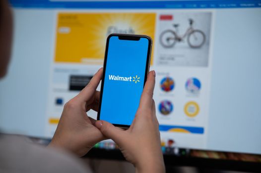 December 3, 2022, Almaty, Kazakhstan: a woman holds a smartphone with a warmart application on the background of a computer