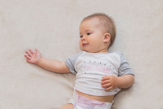 beautiful baby in a diaper is lying on the bed.