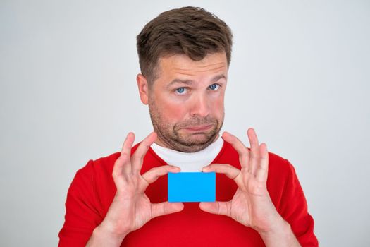 Mature caucasian man looking displeased holding credit card in hands