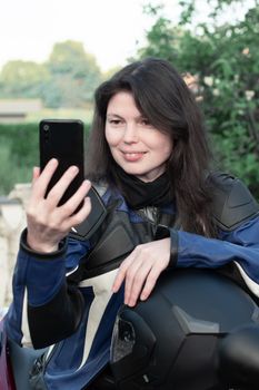 young beautiful brunette biker chatting with friends on a mobile phone, high quality photo. High quality photo