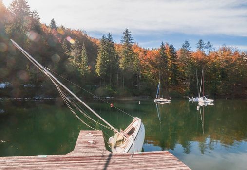 Capsized sailboat near the pier on Lake Bohinj. Autumn landscape in Slovenia