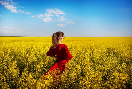 in a red dress beautiful girl standing in a field