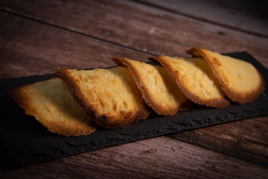French delicacy pastry tuile with almond on wood background, High quality photo