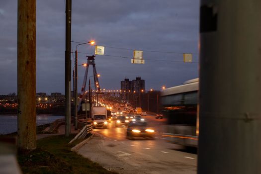 29.11.2022, Cherepovets, Russia. A large automobile bridge on which cars drive at night. A bridge with large columns and lighting. Cars are driving over the bridge