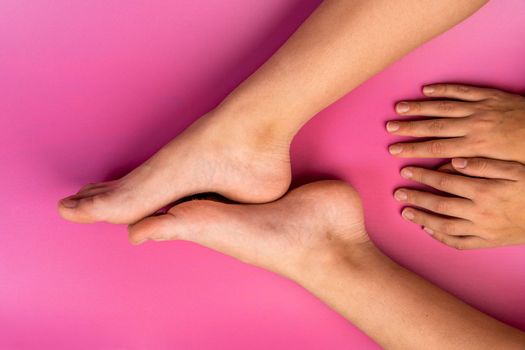 beautiful natural legs and arms of a teenage girl on a pink background, natural female legs and hands, bare feet, fingers,natural beauty of the human body