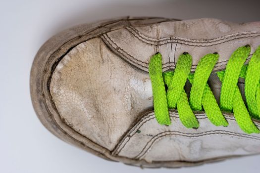 worn old torn white sneakers with colored laces on a white background. Close-up. Fashionable colored acid-colored shoelaces. top view