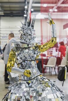 girl in a queen costume made of polished pieces of metal at the international furniture exhibition 