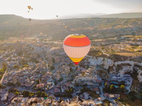 Colorful hot air balloons flying over at fairy chimneys valley in Nevsehir, Goreme, Cappadocia Turkey. Spectacular panoramic drone view of the underground city and ballooning tourism. High quality.