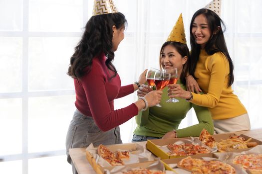 Group of happy young Asian people with friends celebrating clinking glasses during dinner party.