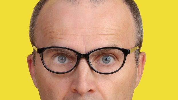 Close-up of a man's face with glasses. Glasses on a man's face close-up on a yellow background.