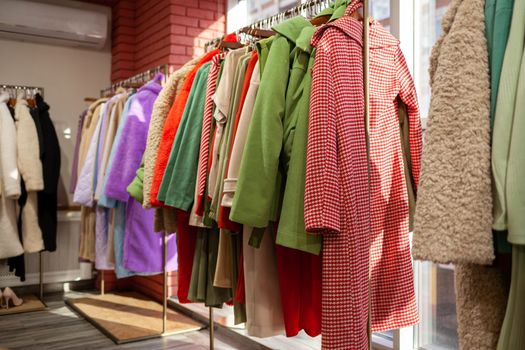 Colorful women's dresses, jackets, trousers and other clothes on hangers in a retail store. The concept of fashion and shopping. Women's clothing boutique.