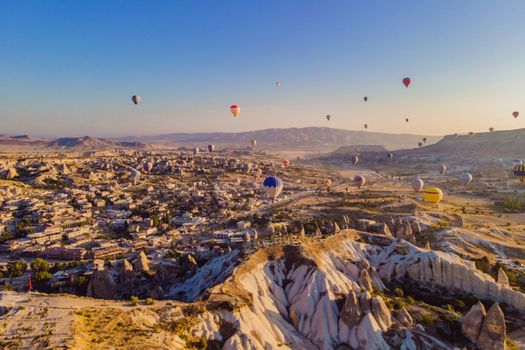 Colorful hot air balloons flying over at fairy chimneys valley in Nevsehir, Goreme, Cappadocia Turkey. Spectacular panoramic drone view of the underground city and ballooning tourism. High quality.