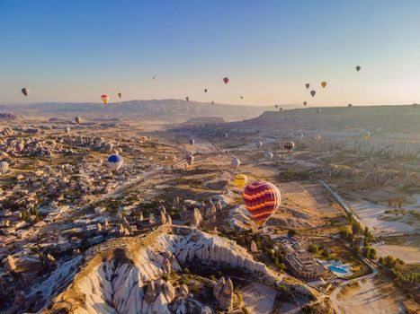 Colorful hot air balloons flying over at fairy chimneys valley in Nevsehir, Goreme, Cappadocia Turkey. Spectacular panoramic drone view of the underground city and ballooning tourism. High quality.