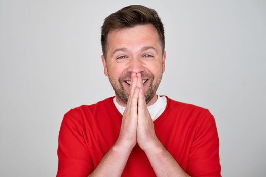 Amazed excited man does not believe his success, keeps hands near mouth, stares at camera, says wow. Pleasant surprised male rejoices good news.