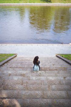 Beautiful girl sits and looks at the river Vilnius - Lithuania.