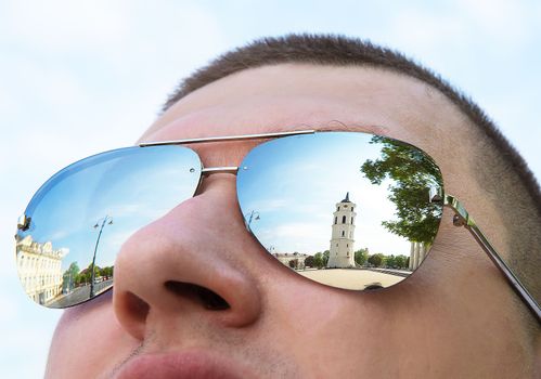 The beautiful city of Vilnius is reflected in a man sunglasses