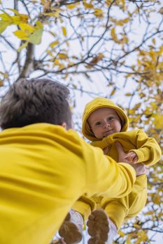 happy father holding his baby daughter smiling walking outdoor on autumn day